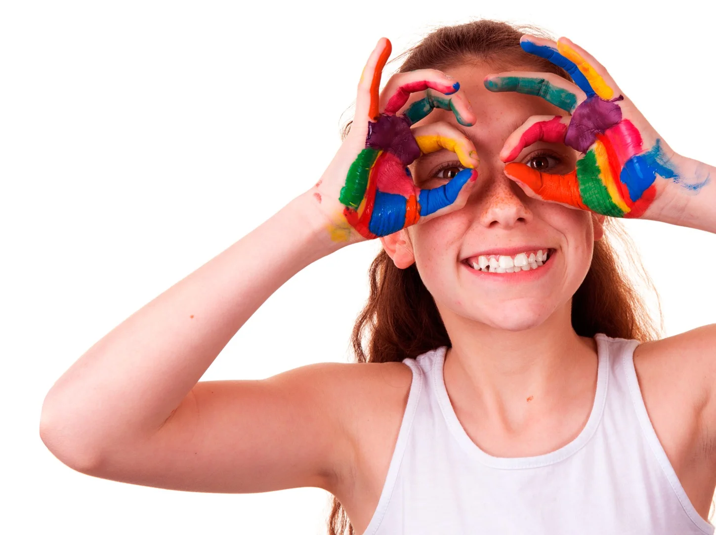 Girl with colorful paint on hands making circles around eyes, smiling.