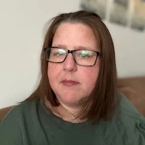 Woman wearing glasses, with brown hair and a green top.