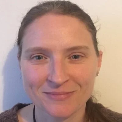 Close-up of a woman with blue eyes, smiling, looking at the camera.