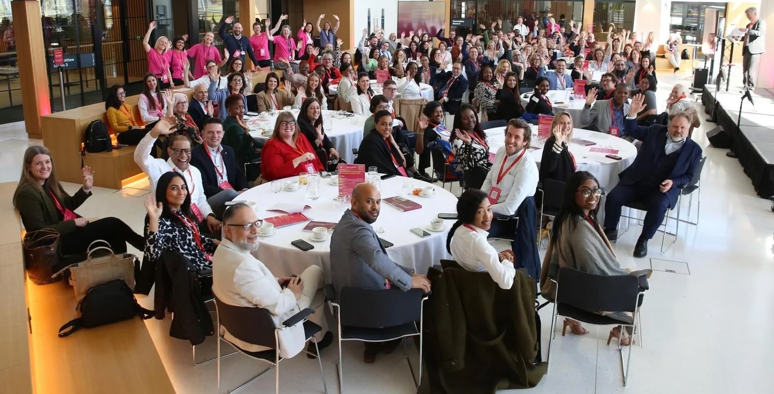 Large group of people at an event, many waving.